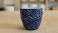 Blauer Keramikbecher mit geschnitzten Motiven 